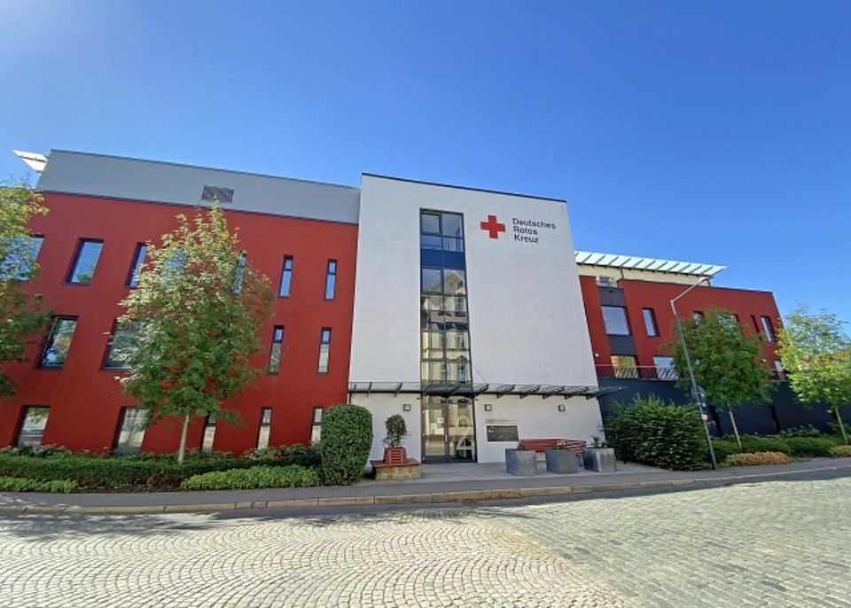 Außenansicht des modernen DRK Pflegeheims Haus Fischerstadt in rot-weißer Fassade.