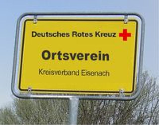 Ein gelbes, rechteckiges Schild in Form eines Ortsschildes mit der Aufschrift: 'Deutsches Rotes Kreuz', einem roten Kreuz-Symbol, dem Wort 'Ortsverein' in fetter Schrift und der Ergänzung 'Kreisverband Eisenach'.
