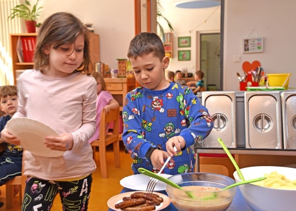 Zwei Kinder bedienen sich selbstständig am Buffet während des gemeinsamen Mittagessens im Kindergarten.