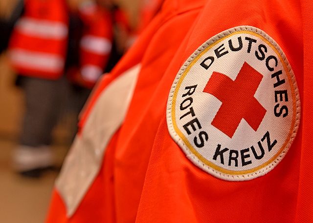 Nahaufnahme eines Ärmelabzeichens des Deutschen Roten Kreuzes auf einer roten Einsatzjacke.